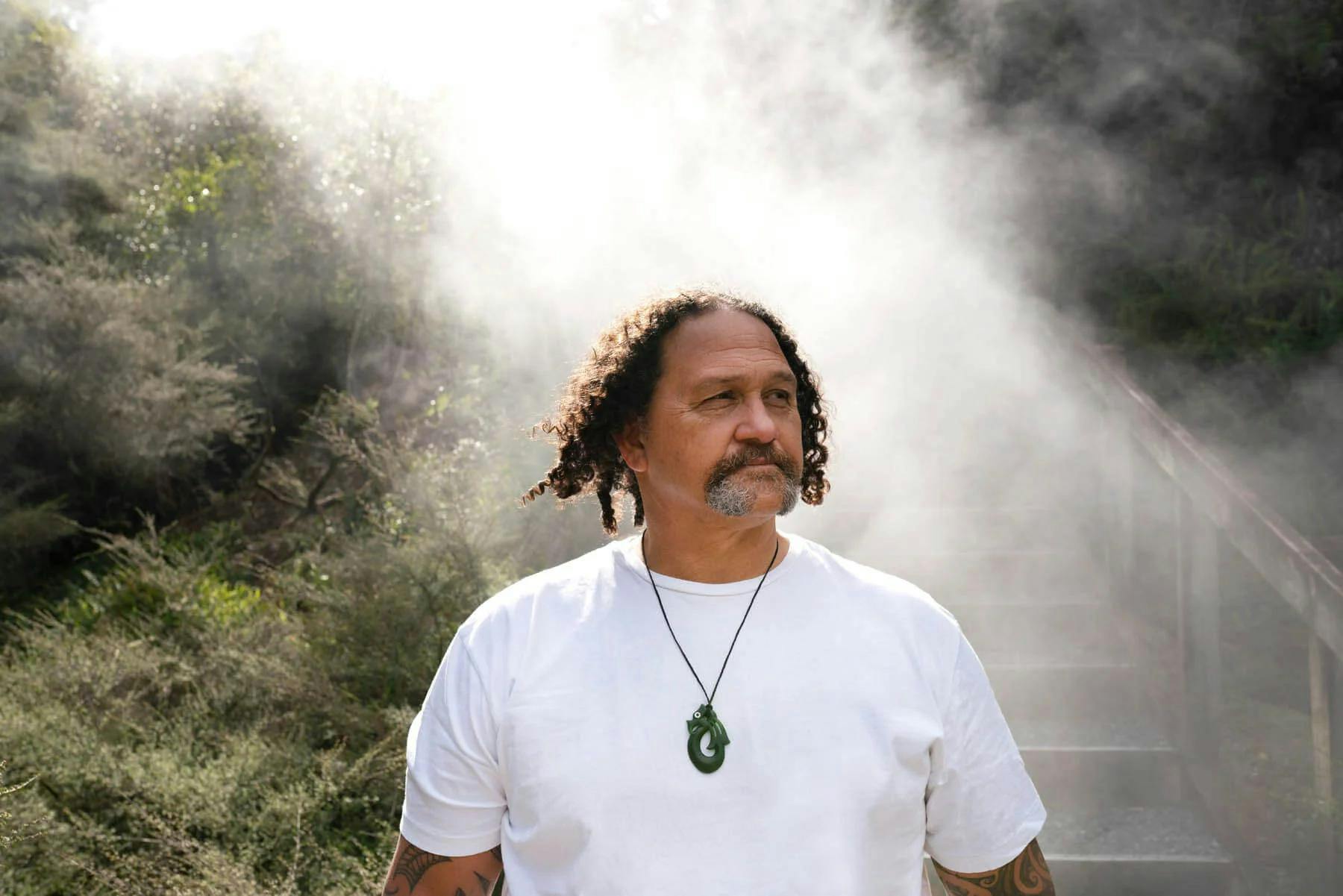 Man wearing manaia necklace with a misty backdrop