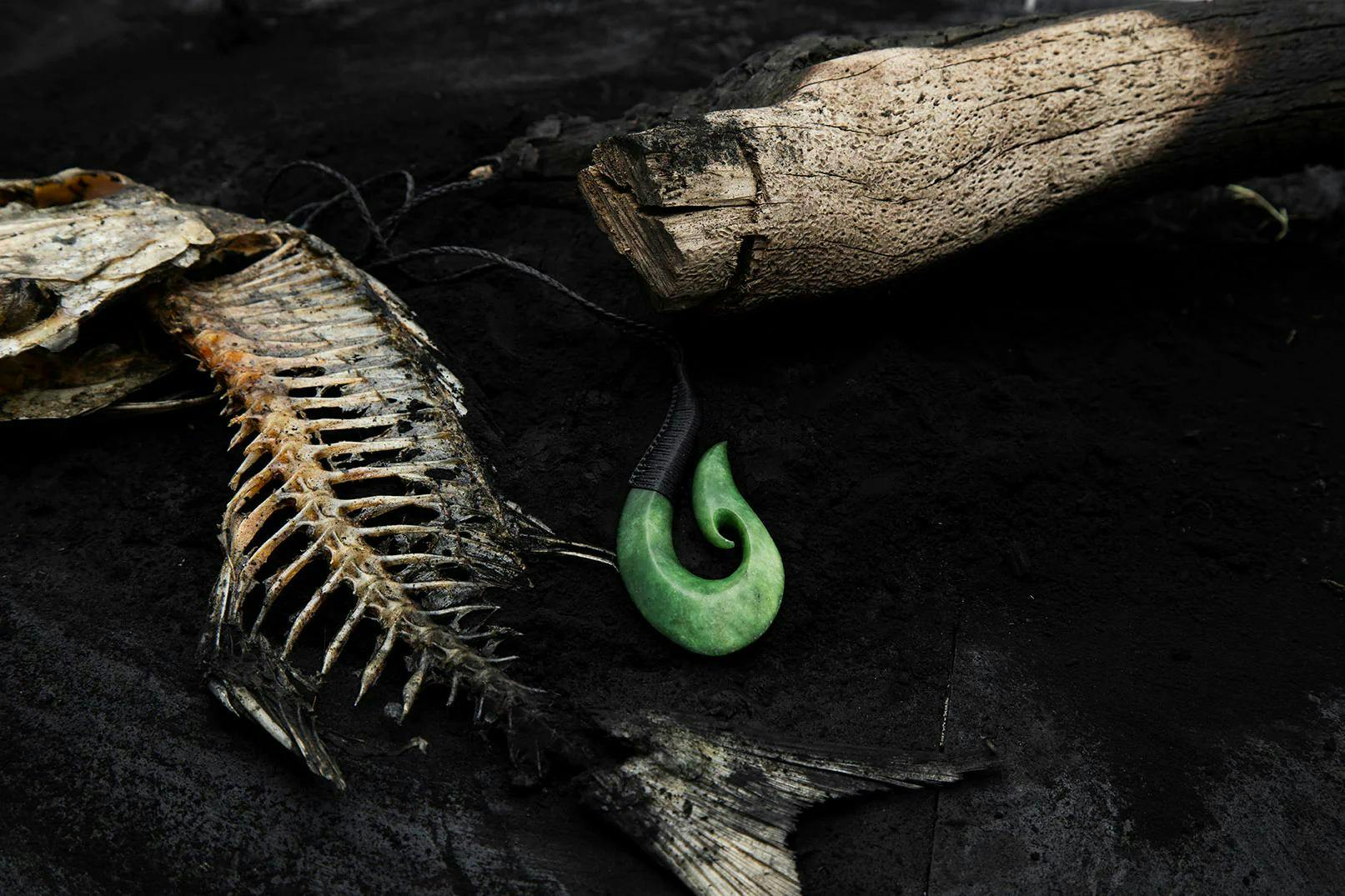 Hei matau pendant amongst fish skeleton and a log