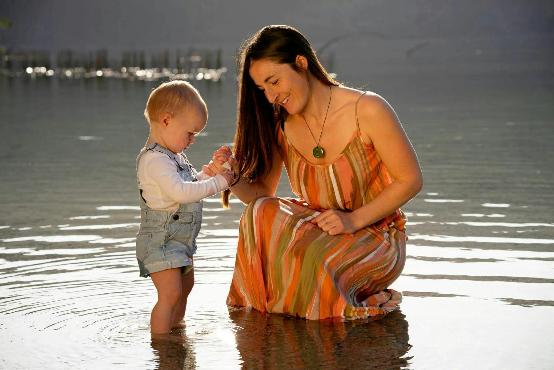 Woman wearing koru in the river with a baby