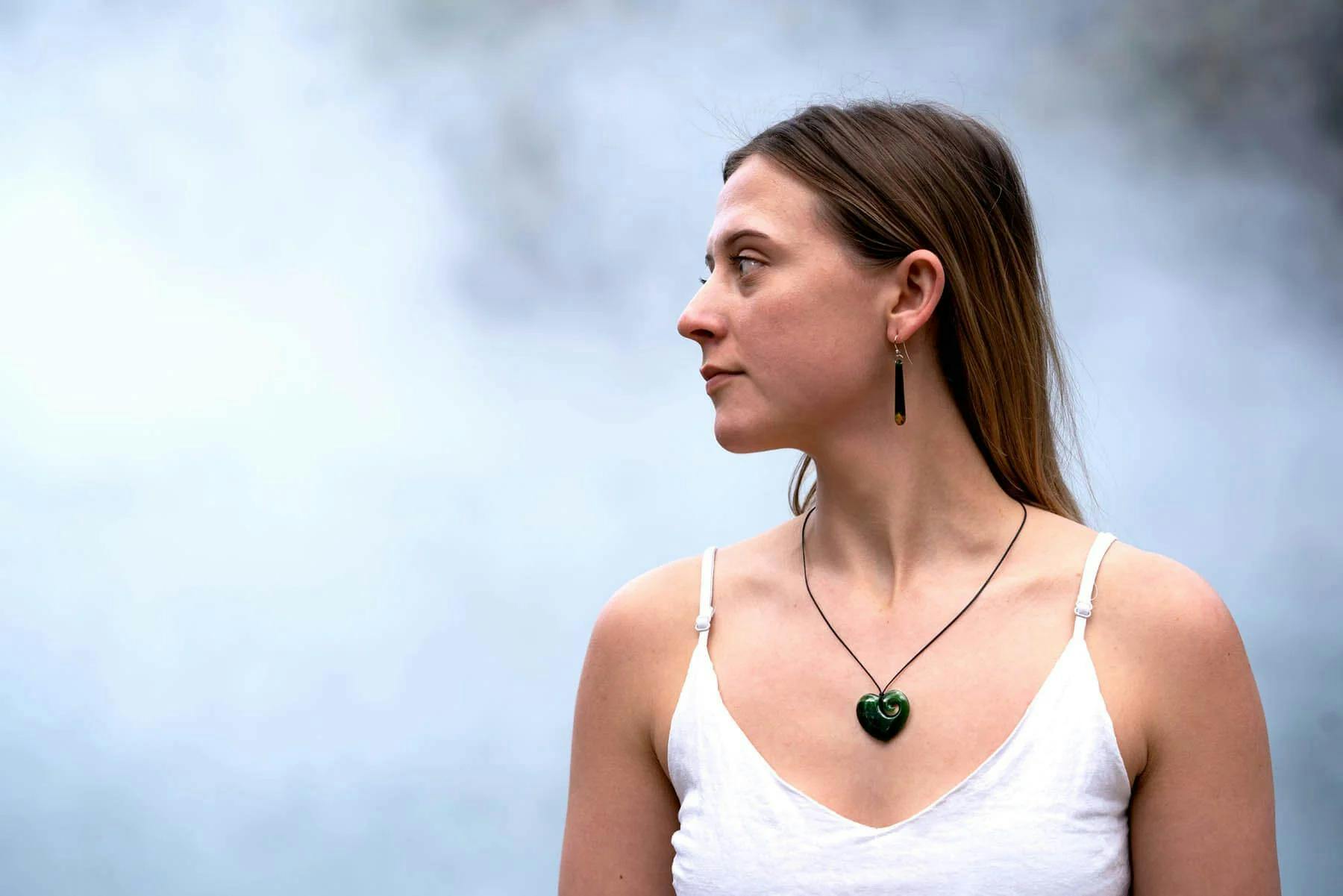 Woman wearing heart necklace with a misty backdrop